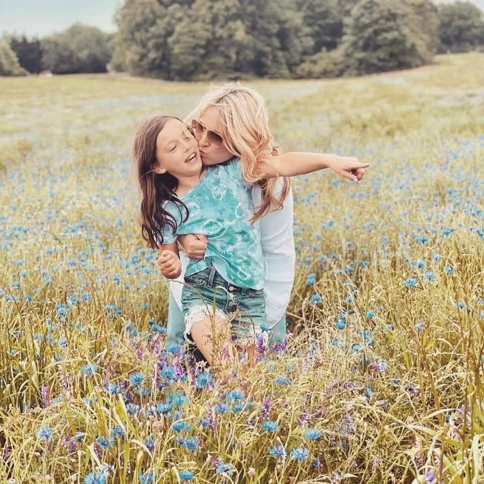 A kiss on the cheek in a field of wildflowers